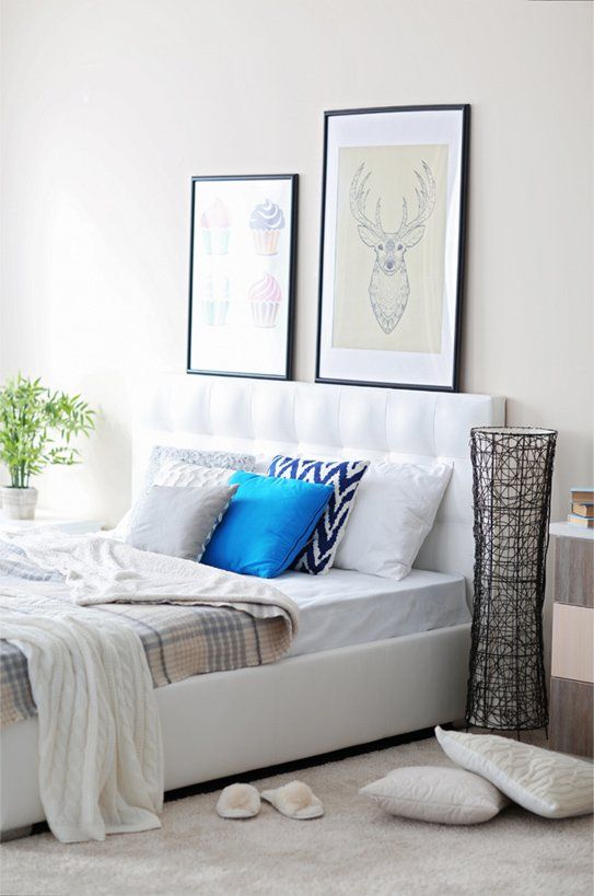 A white bedroom with blue pillows and light grey carpeting