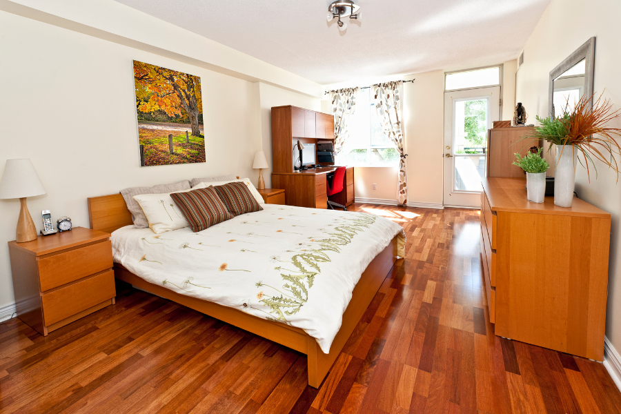 A bedroom with engineered hardwood floors and a large bed