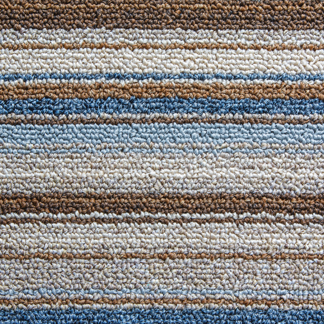 A close up of a striped carpet with blue and brown stripes.