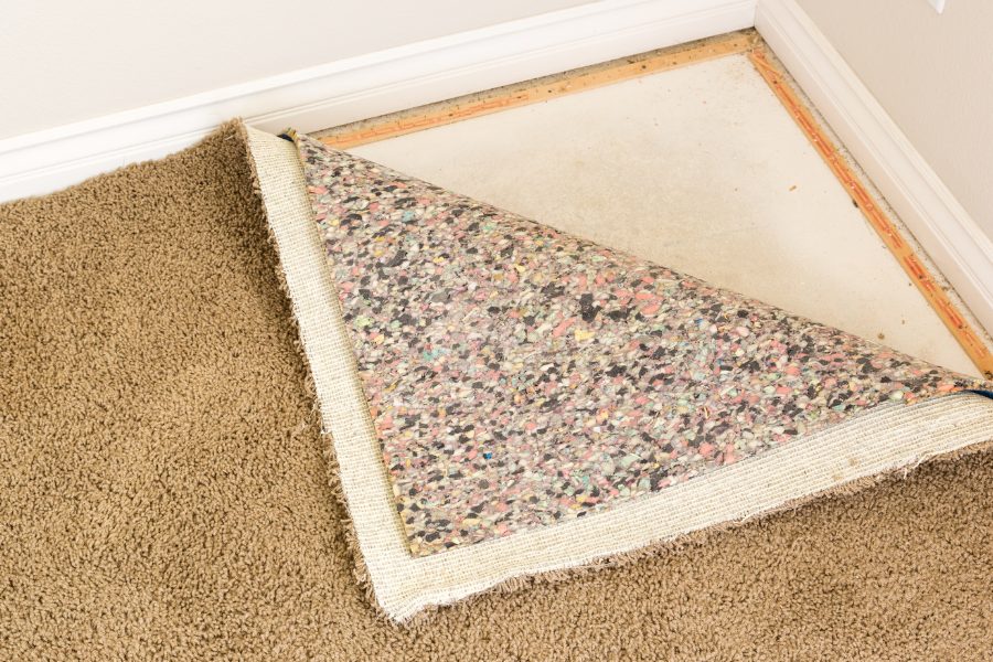 A piece of carpet with rubber padding is laying on the floor in a room.