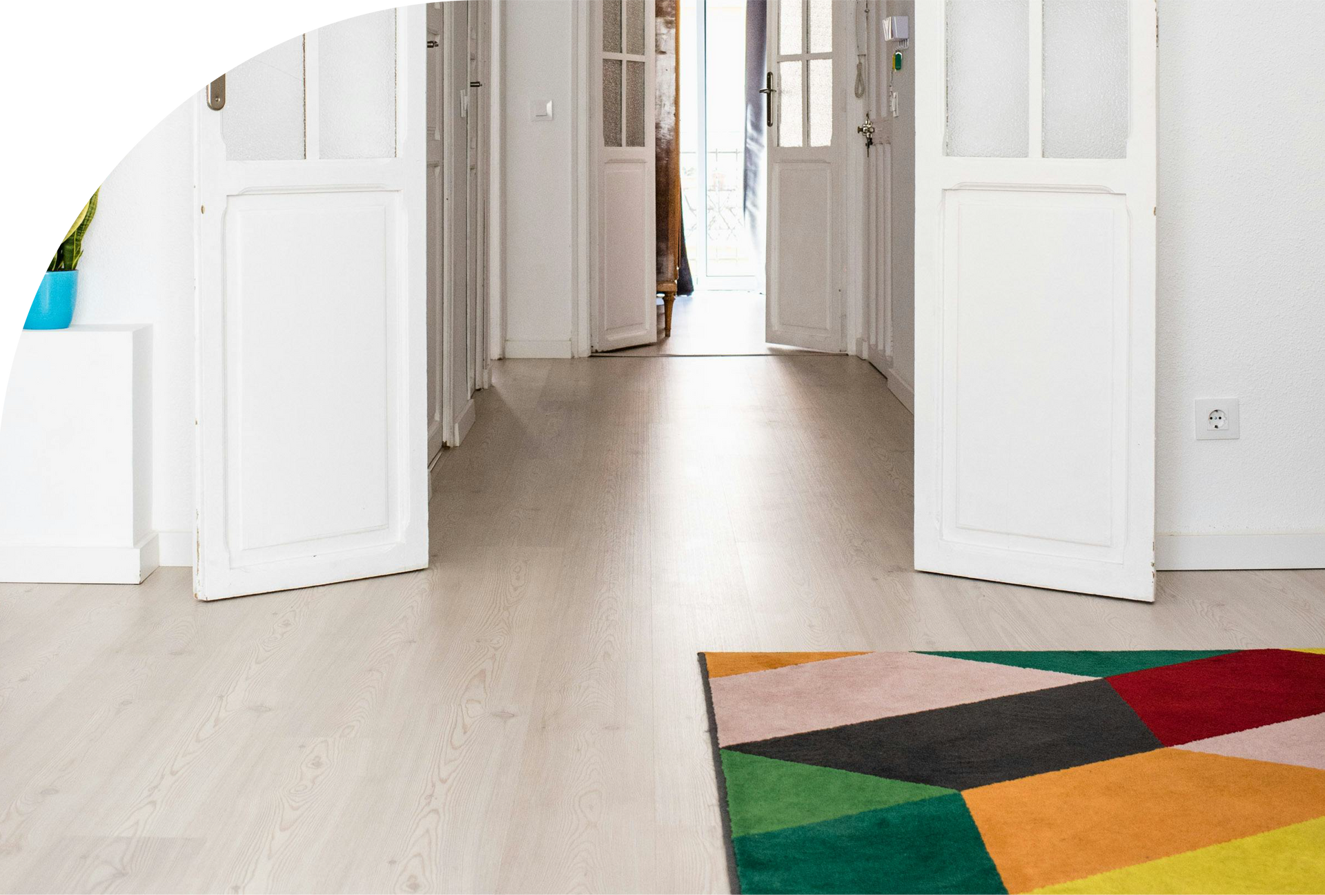 A hallway with white doors and a colorful rug on the floor.
