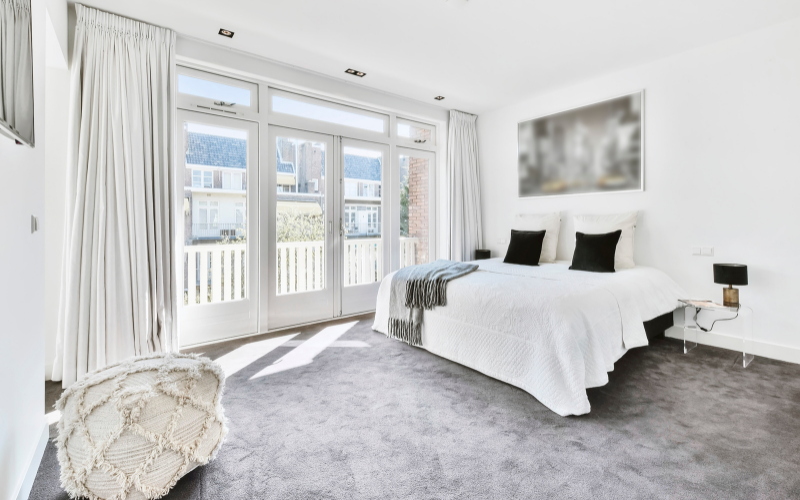 A carpeted bedroom with a large bed and a balcony