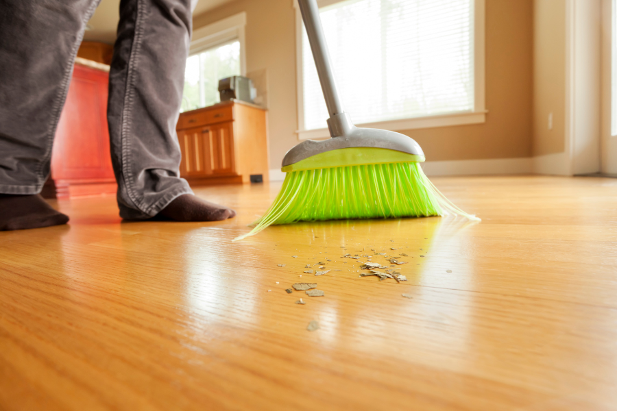 A person is sweeping the floor with a green broom.