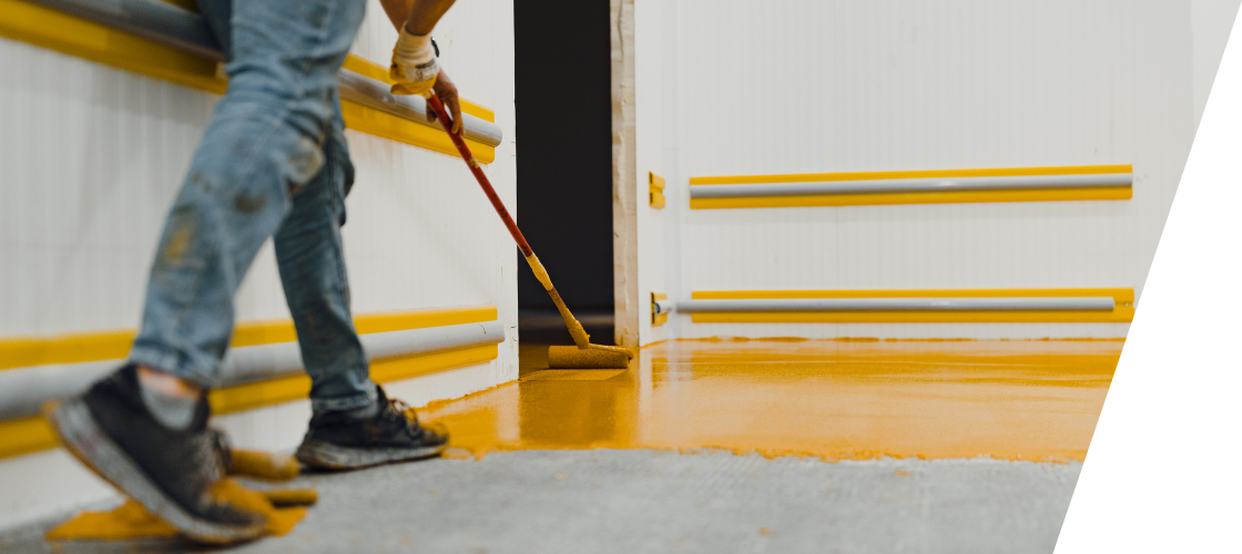 A person is painting a floor with a roller.