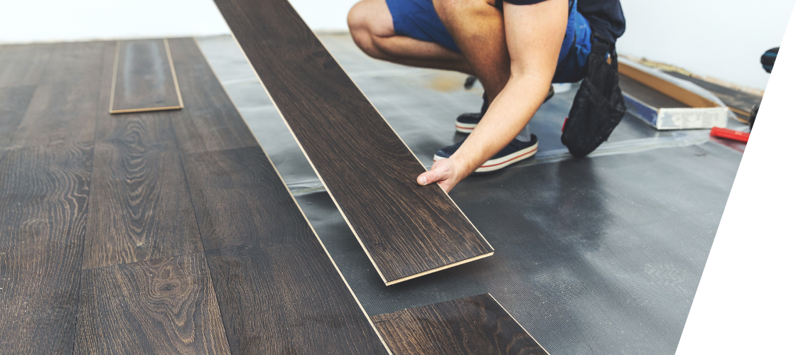 A person is installing a wooden floor in a room.