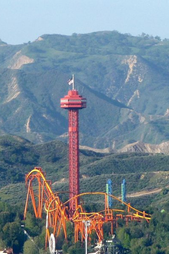 Six Flags Magic Mountain, a roller coaster is in the middle of a park with mountains in the background