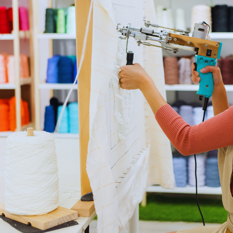 A woman is using a machine to cut a piece of fabric