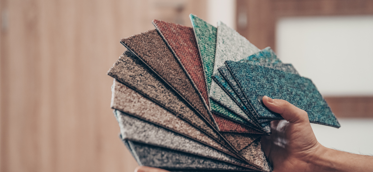 A person is holding a fan of carpet samples in their hand.