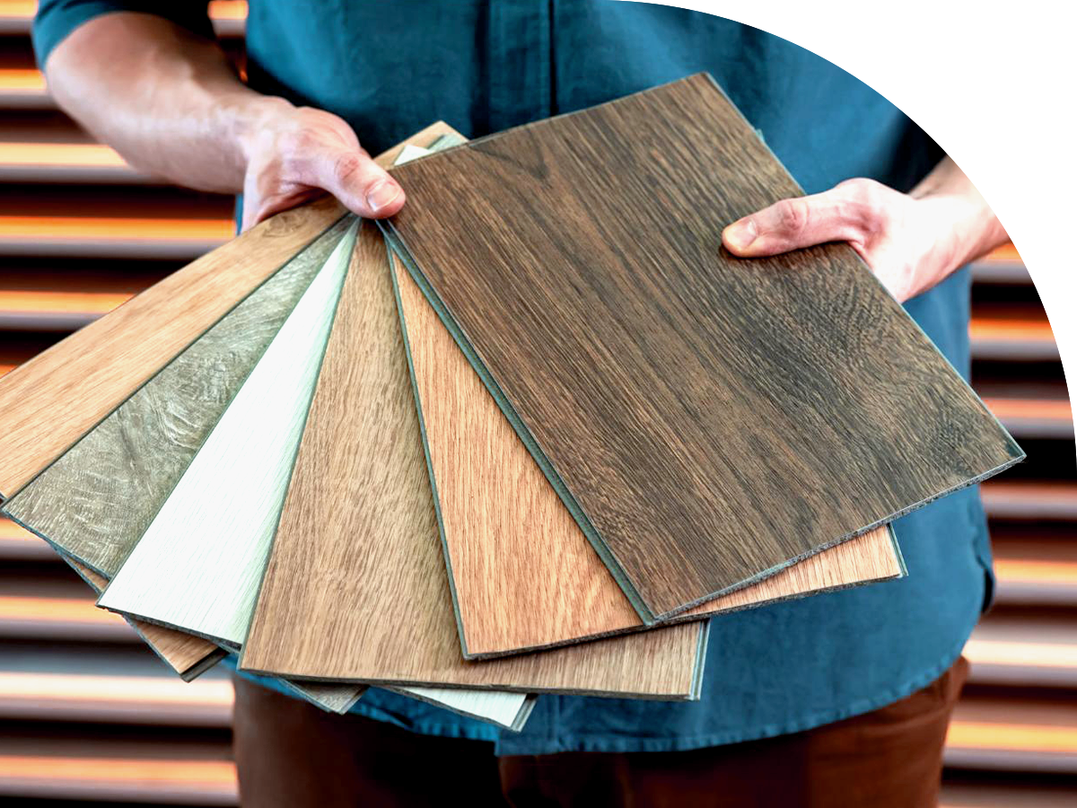 A man holding a variety of LVP floors samples.