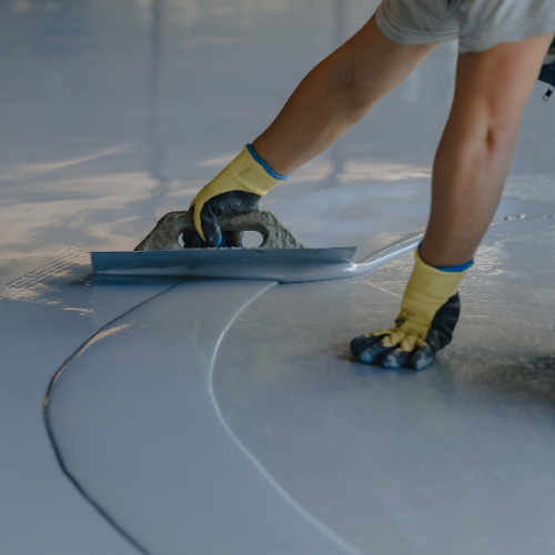 A man is working on a concrete floor coated with epoxy.