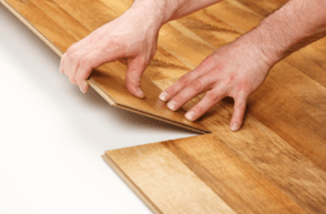 close up of hands installing a hardwood floor