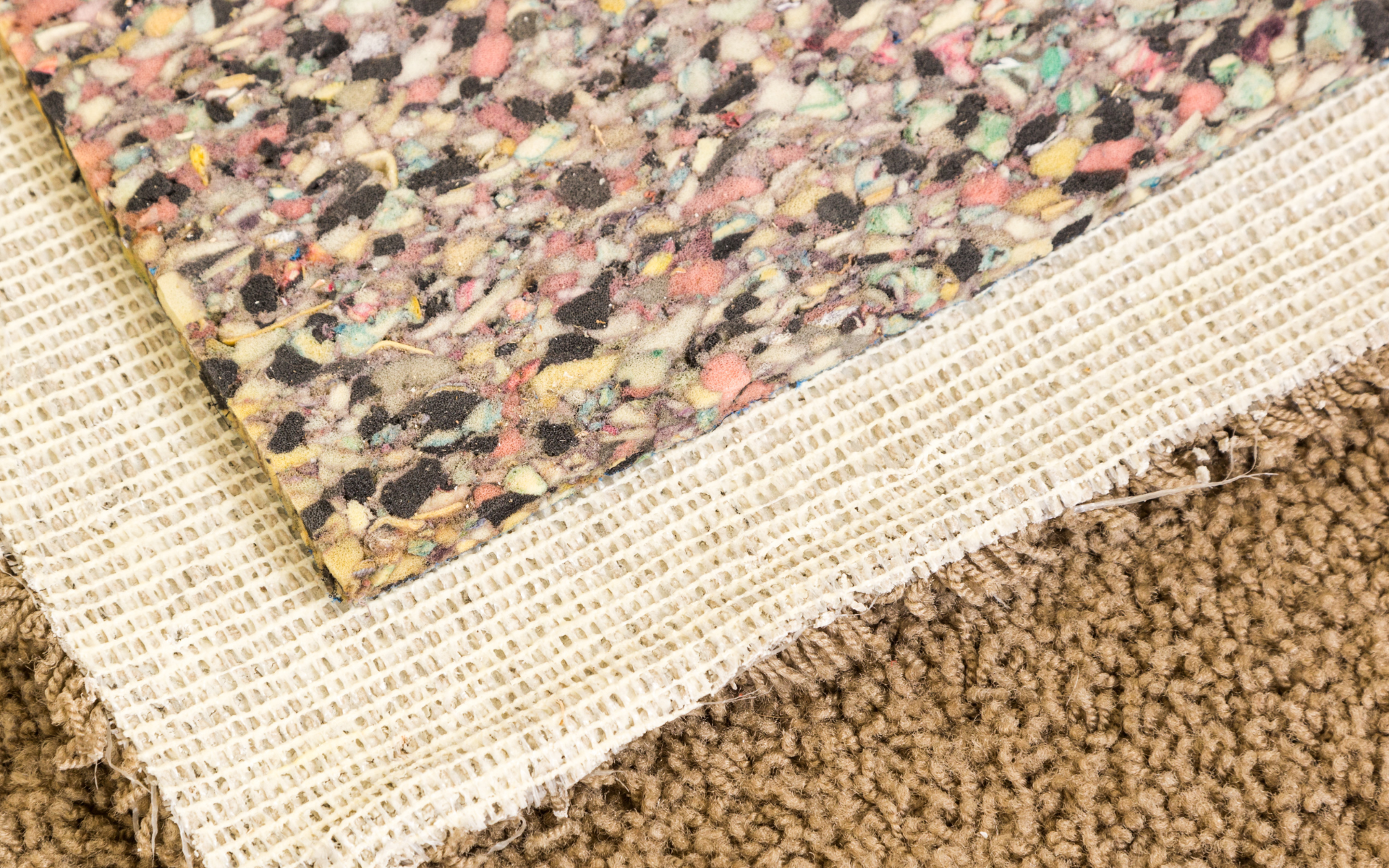 A close up of a piece of carpet next to a piece of foam.