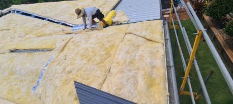 Roofer Working on a Roof Covered in Insulation, Near Scaffolding, in Daylight — Venom Roofing Pty Ltd in Sunshine Coast, QLD