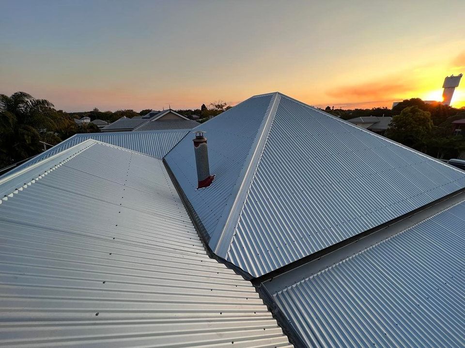 Metal Roof With a Chimney Against a Sunset, Seen From Above — Venom Roofing Pty Ltd in Landsborough, QLD