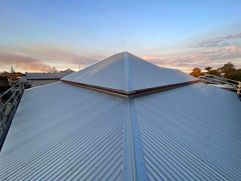 Silver Corrugated Metal Roof With a Peaked Center, Blue Sky Background — Venom Roofing Pty Ltd in Landsborough, QLD