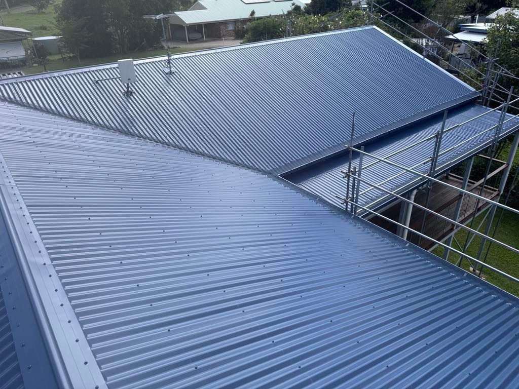 Gray Corrugated Metal Roof With Scaffolding on a Building Exterior — Venom Roofing Pty Ltd in Sunshine Coast, QLD