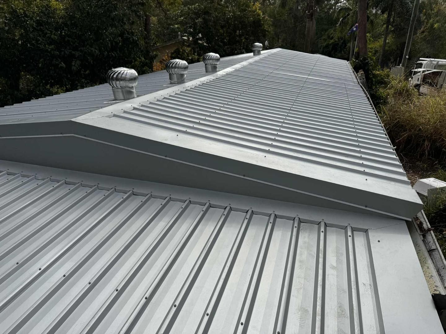 a Metal Roof With Ridges, a Few Vents, and a Sloped Section — Venom Roofing Pty Ltd in Sunshine Coast, QLD