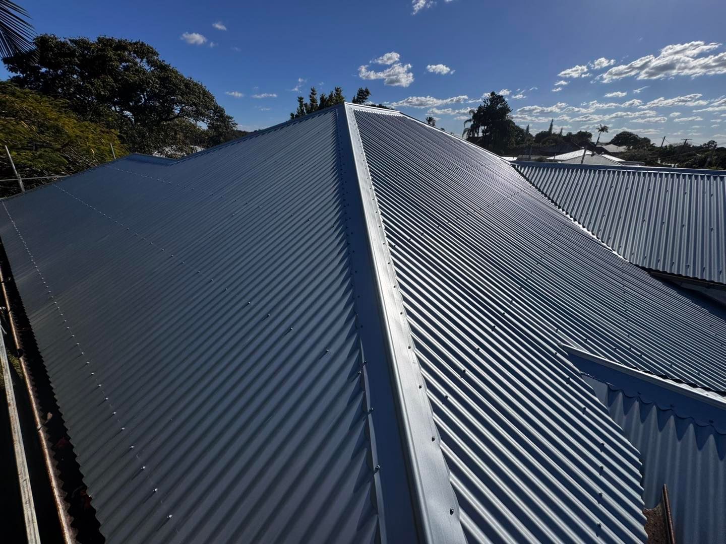 Gray Corrugated Metal Roof Under a Partly Cloudy Blue Sky — Venom Roofing Pty Ltd in Sunshine Coast, QLD
