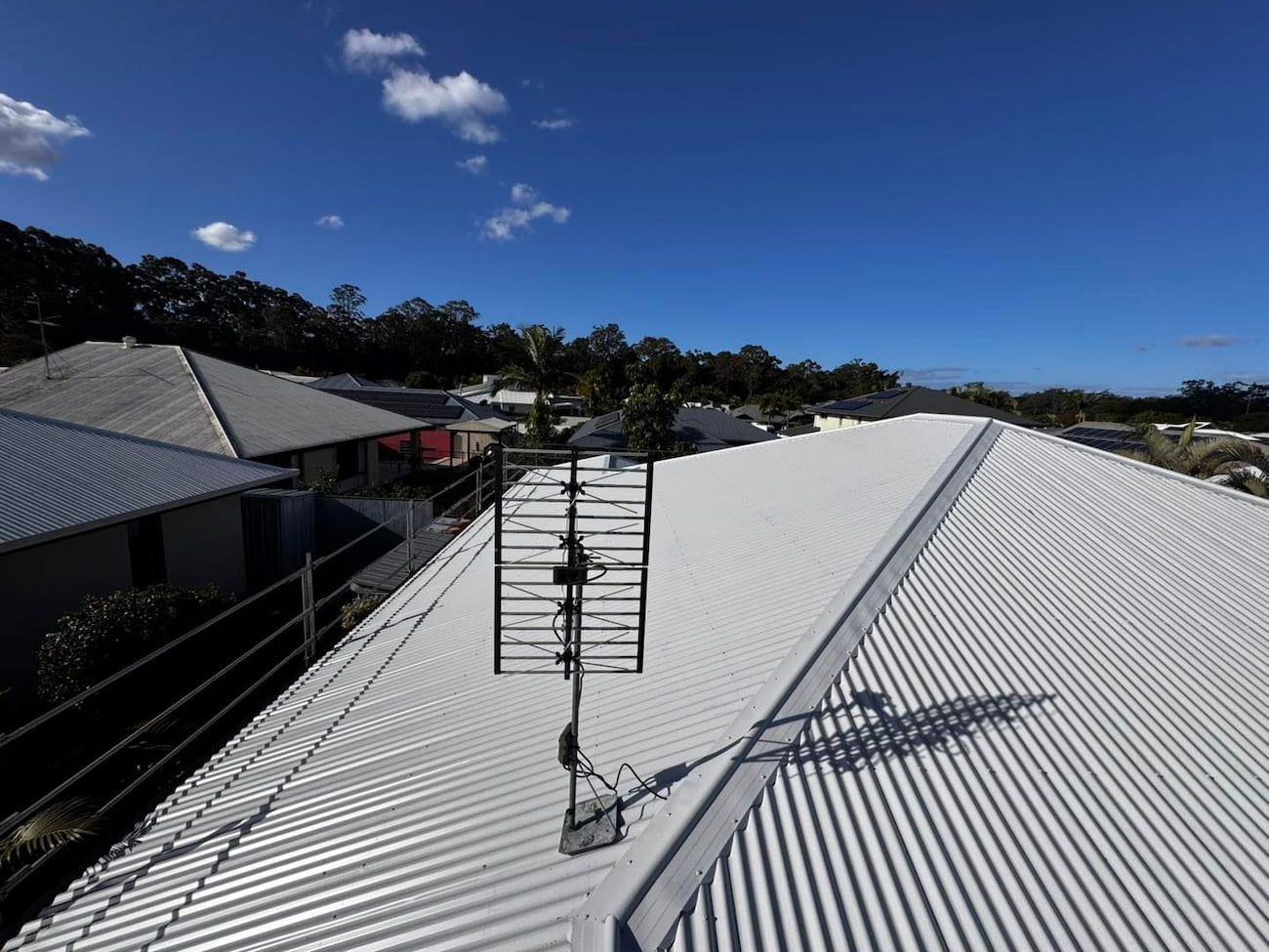 Television Antenna on a White Corrugated Metal Roof Under a Bright Blue Sky — Venom Roofing Pty Ltd in Sunshine Coast, QLD
