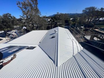 White Corrugated Metal Roof of a Building Under a Bright Blue Sky — Venom Roofing Pty Ltd in Sunshine Coast, QLD