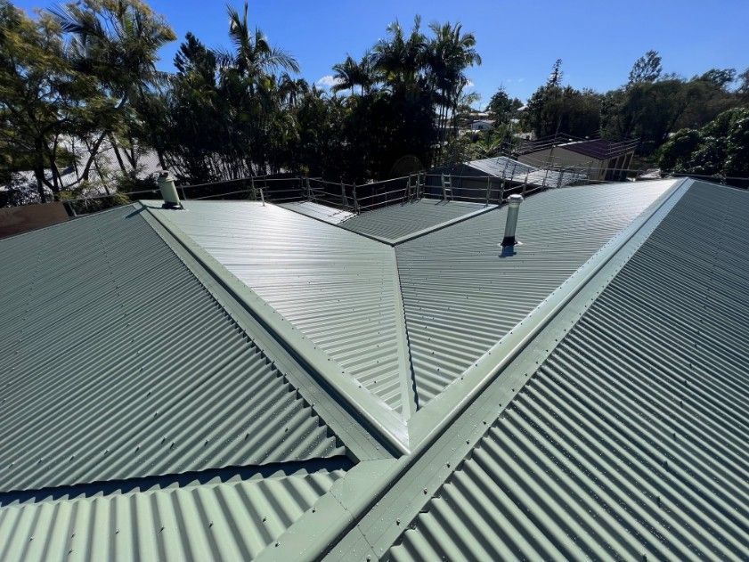 Green Corrugated Metal Roof With Ridge Lines and a Blue Sky — Venom Roofing Pty Ltd in Sunshine Coast, QLD