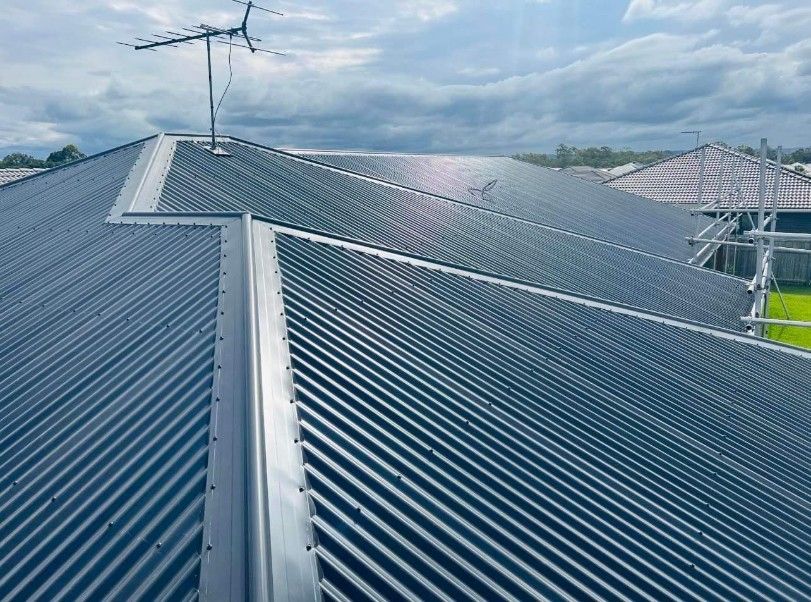 Gray Corrugated Metal Roof With Antenna, Angled Against a Cloudy Sky — Venom Roofing Pty Ltd in Maroochydore, QLD