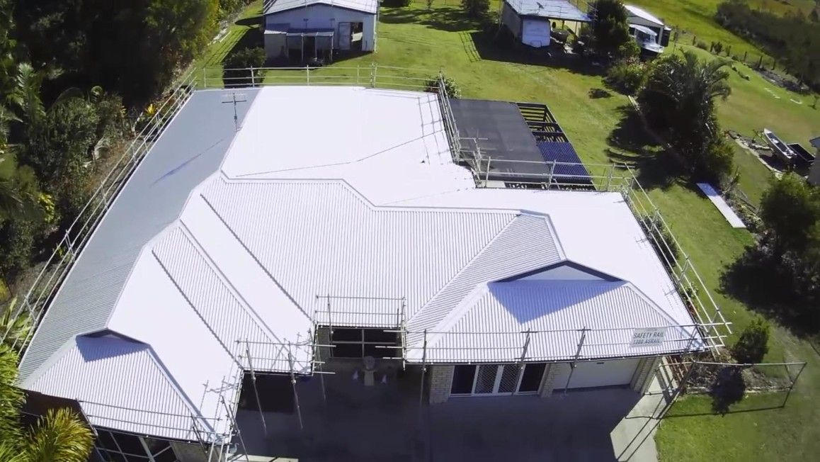Aerial View of a House With a New White Metal Roof and Scaffolding — Venom Roofing Pty Ltd in Sunshine Coast, QLD
