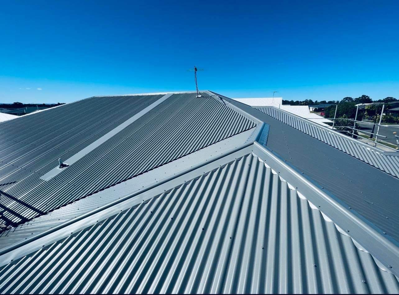 A Grey Corrugated Metal Roof Under a Bright Blue Sky — Venom Roofing Pty Ltd in Sunshine Coast, QLD