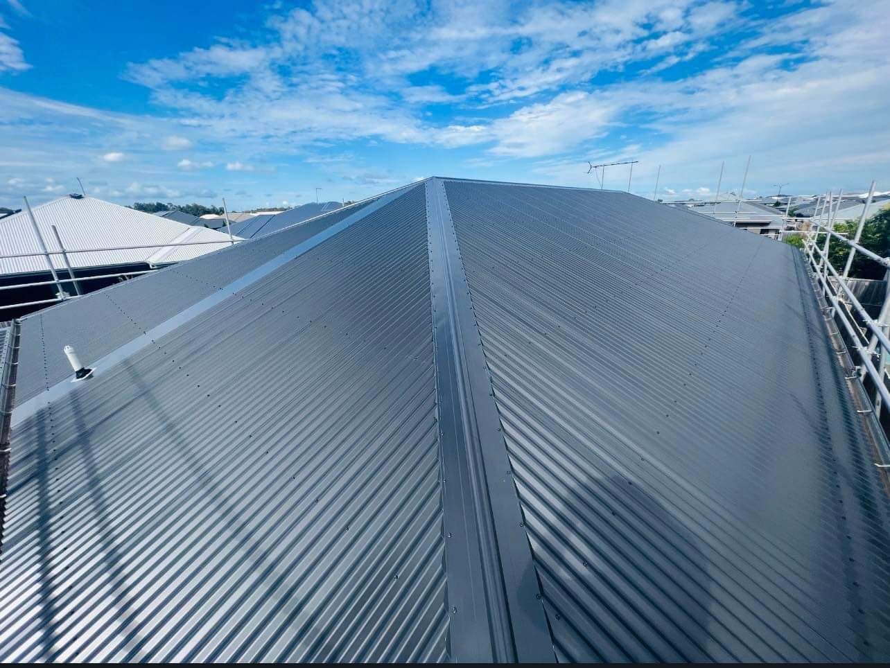 Gray Corrugated Metal Roof With Ridgeline Against a Blue Sky — Venom Roofing Pty Ltd in Sunshine Coast, QLD