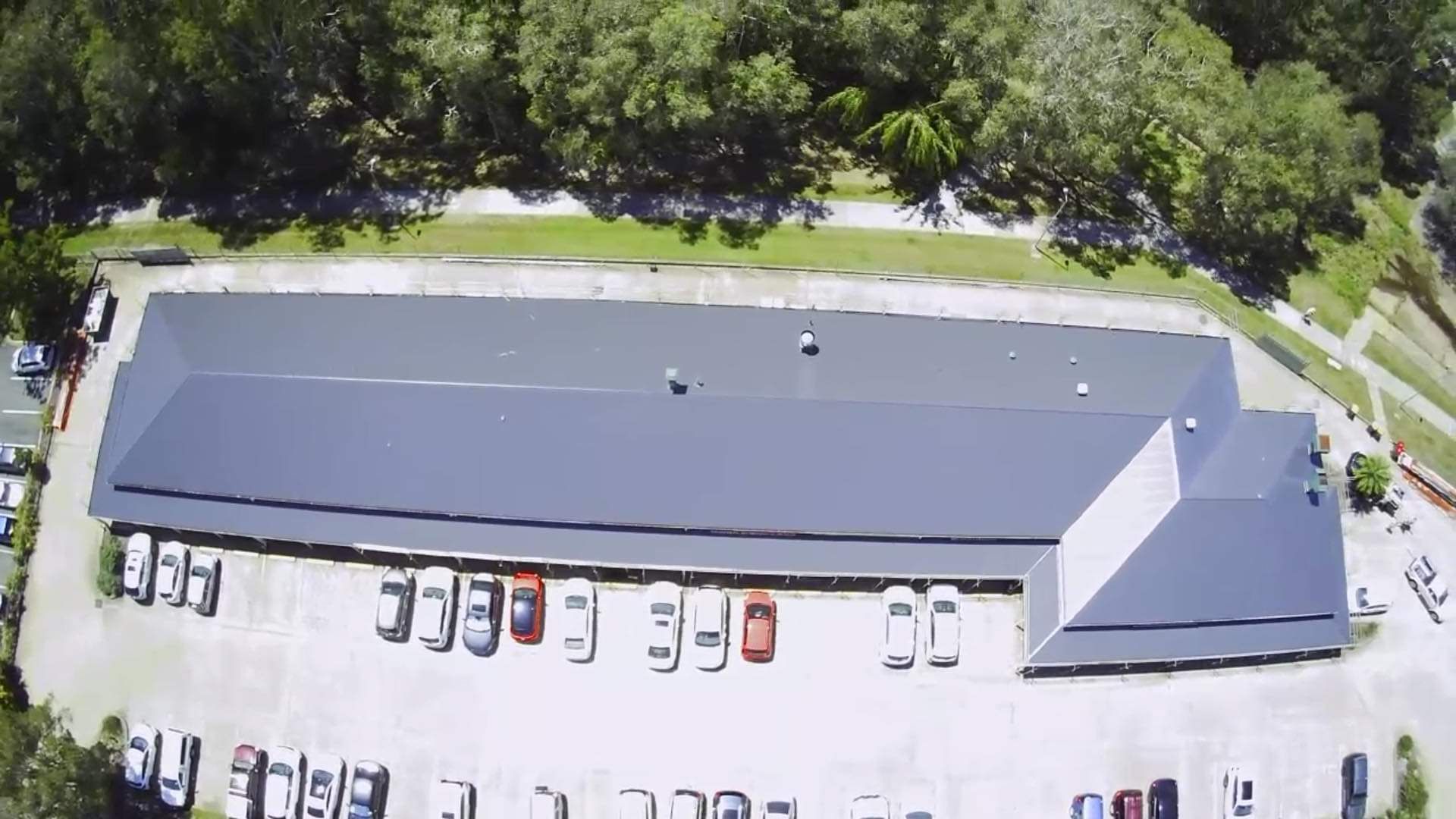 Aerial View of a Long, Gray-roofed Building With Cars Parked in Front — Venom Roofing Pty Ltd in Sunshine Coast, QLD
