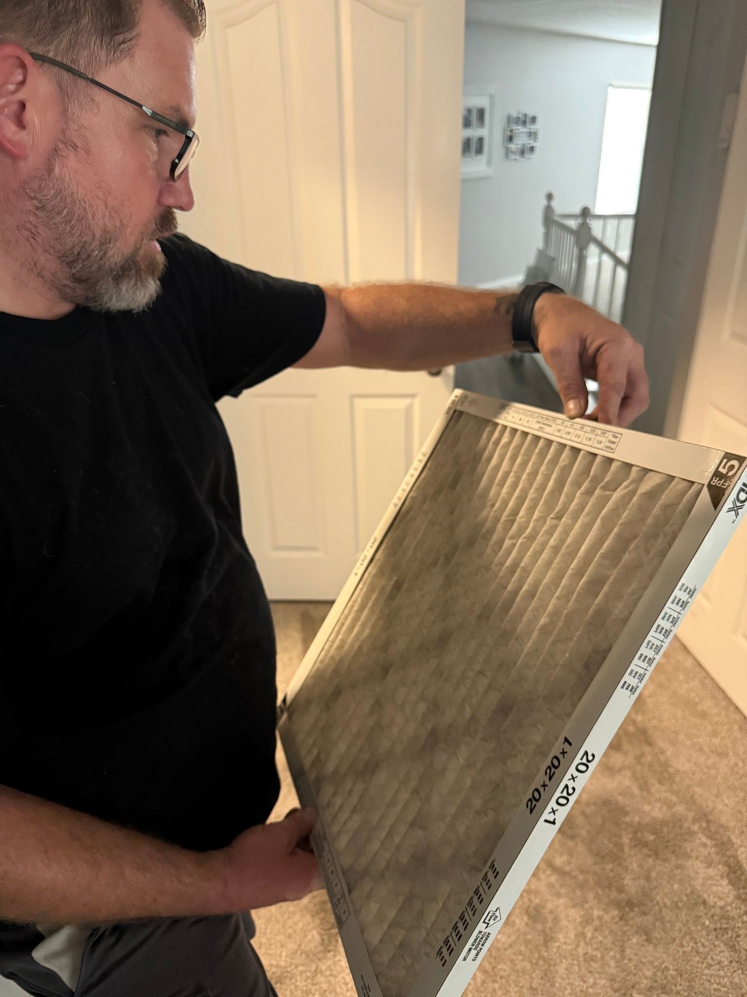 Man holding a very dirty air filter indoors, likely checking or changing it.