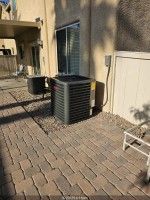 Air conditioner unit on a wooden pallet in a driveway, with garage and vehicle in background.
