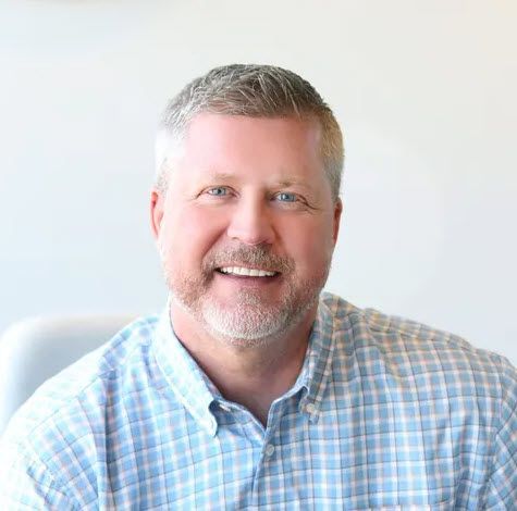 A man and a woman are sitting on a dock overlooking a lake.