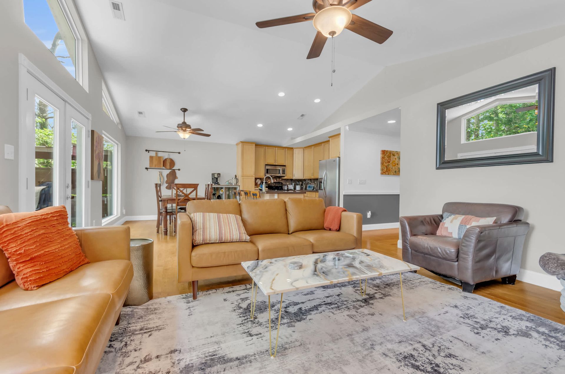 Spacious living room with tan leather sofa, marble coffee table, and light wood floors.