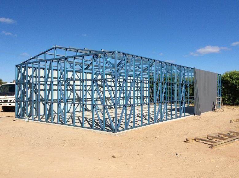 A Blue Metal Frame of a Building Under Construction on a Dirt Lot — Bridgey's Constructions in Forster, NSW