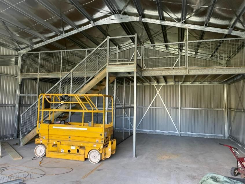 Yellow Scissor Lift Inside a Metal Building — Bridgey's Constructions in Laurieton, NSW