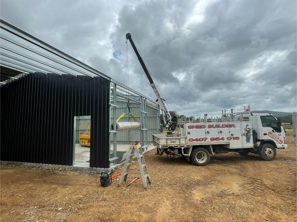 Crane Lifting a Tank Near a Metal-framed Building Under Construction — Bridgey's Constructions in Wauchope, NSW