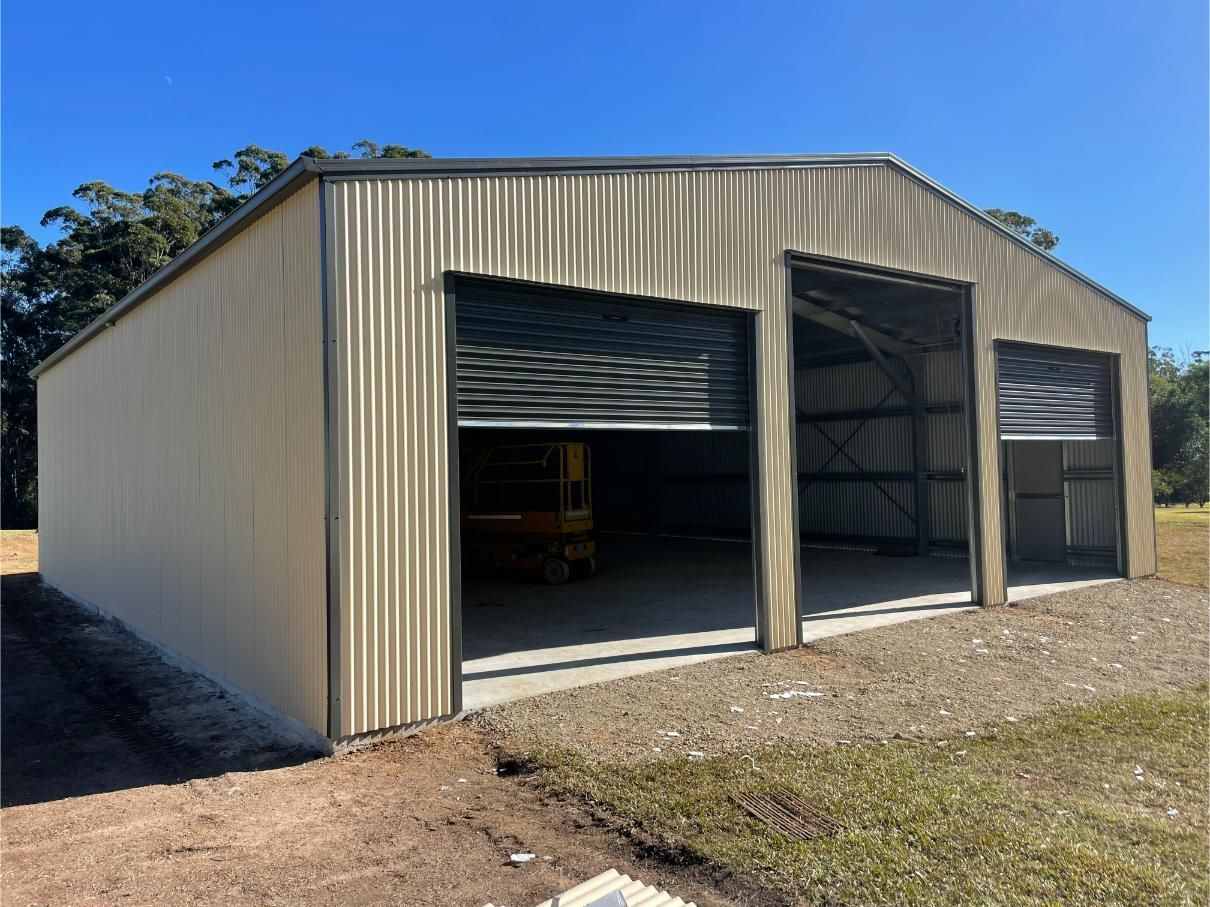 A Light-Tan Metal Shed With Two Open Garage Doors — Bridgey's Constructions in Laurieton, NSW