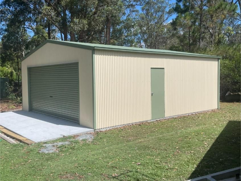 Tan Metal Shed With a Green Roller Door and Matching Trim — Bridgey's Constructions in Forster, NSW