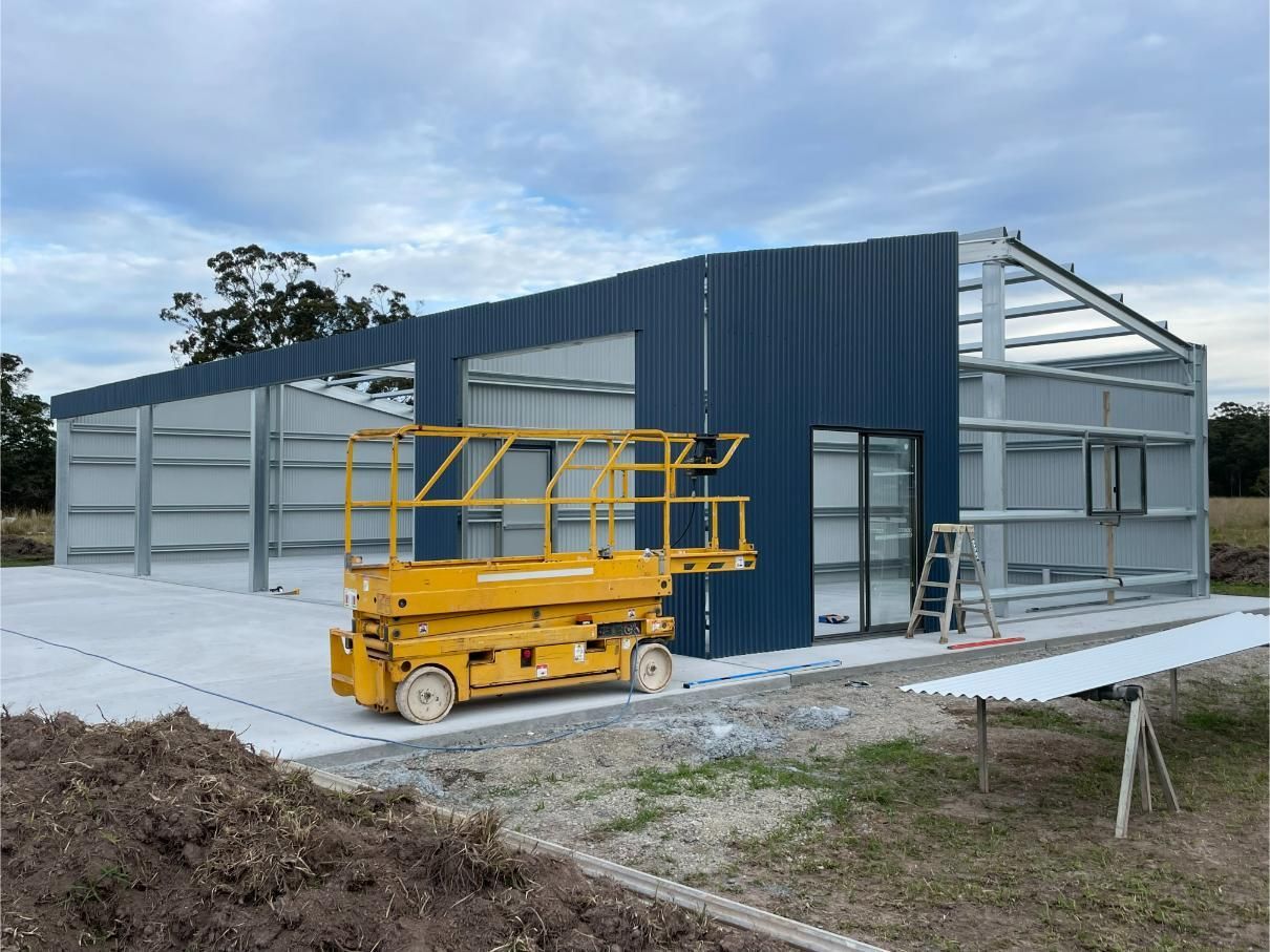 Construction Site: a Partially Built Metal Building With Dark Blue Panels — Bridgey's Constructions in Wingham, NSW