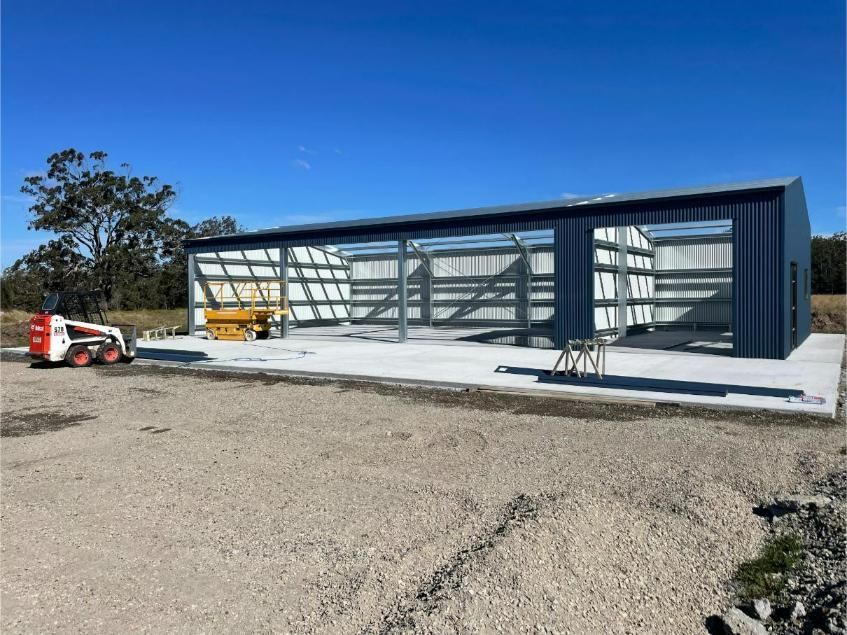 A Partially Built Blue Metal Building With a Concrete Slab Foundation — Bridgey's Constructions in Manning Point, NSW