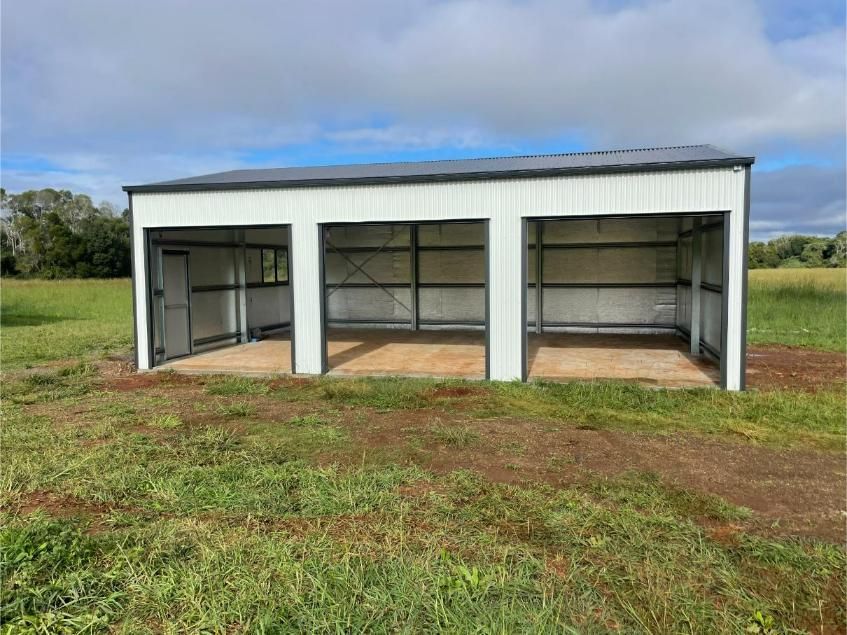 White and Grey Metal Shed With Three Bays in a Grassy Field Under a Cloudy Sky — Bridgey's Constructions in Gloucester, NSW
