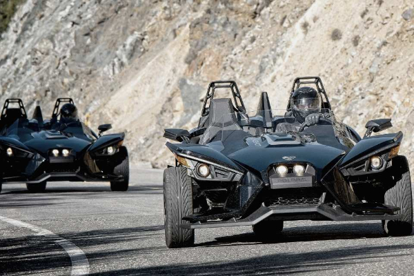 Three slingshot motorcycles are driving down a road.
