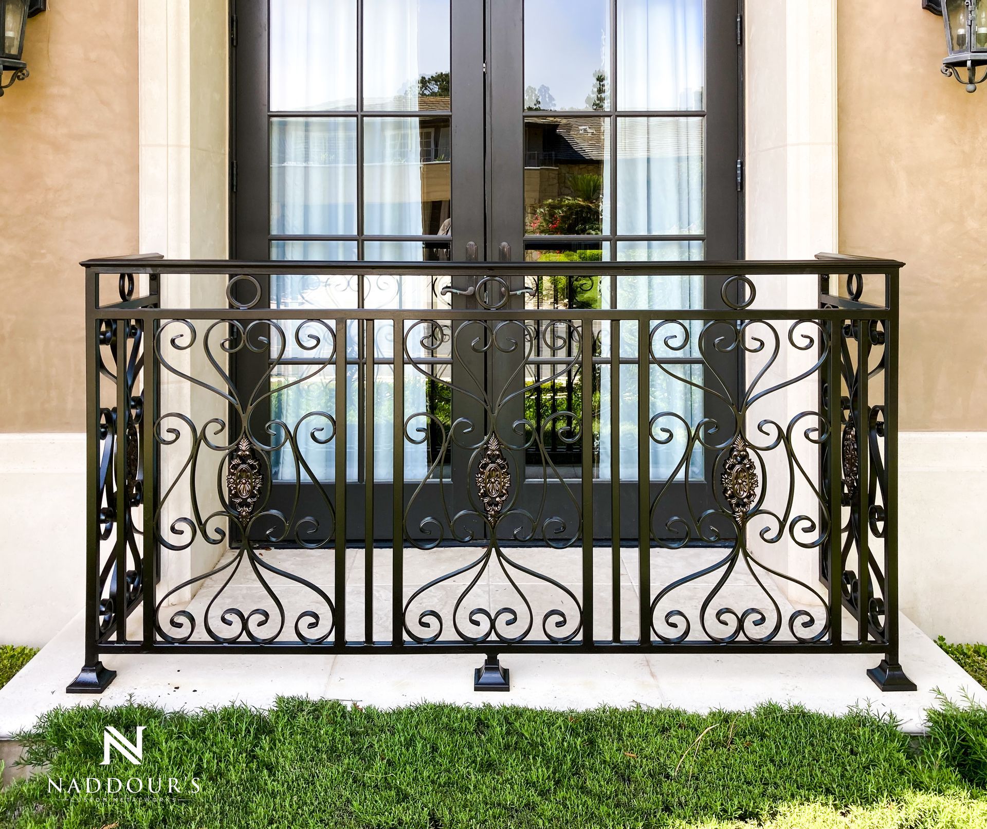 A wrought iron railing is surrounding a balcony with a window.