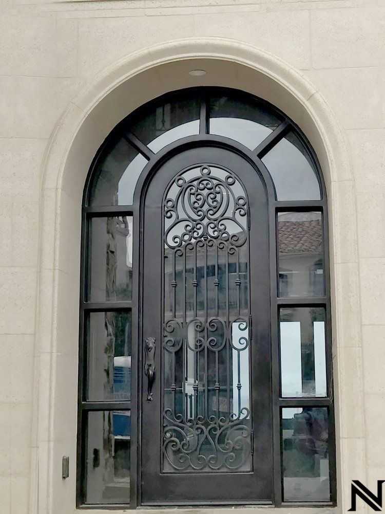 A wrought iron door with a round window on the side of a building.