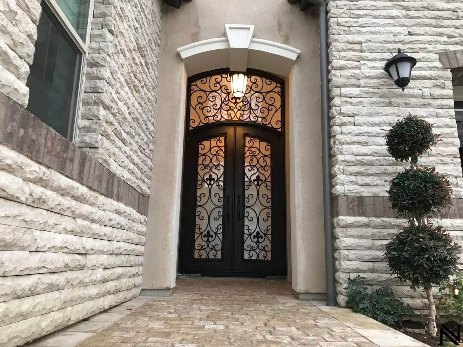 A brick building with a black door and a lamp on the side of it.