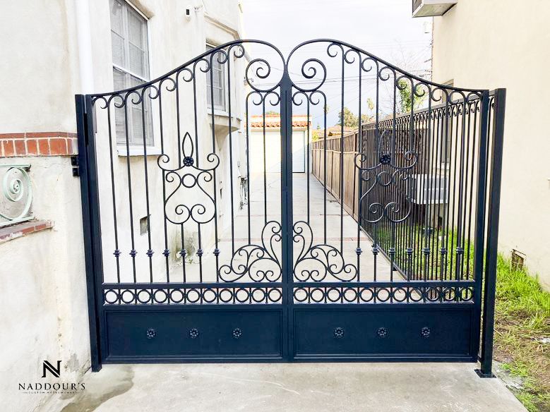 A black wrought iron gate is sitting in front of a house.