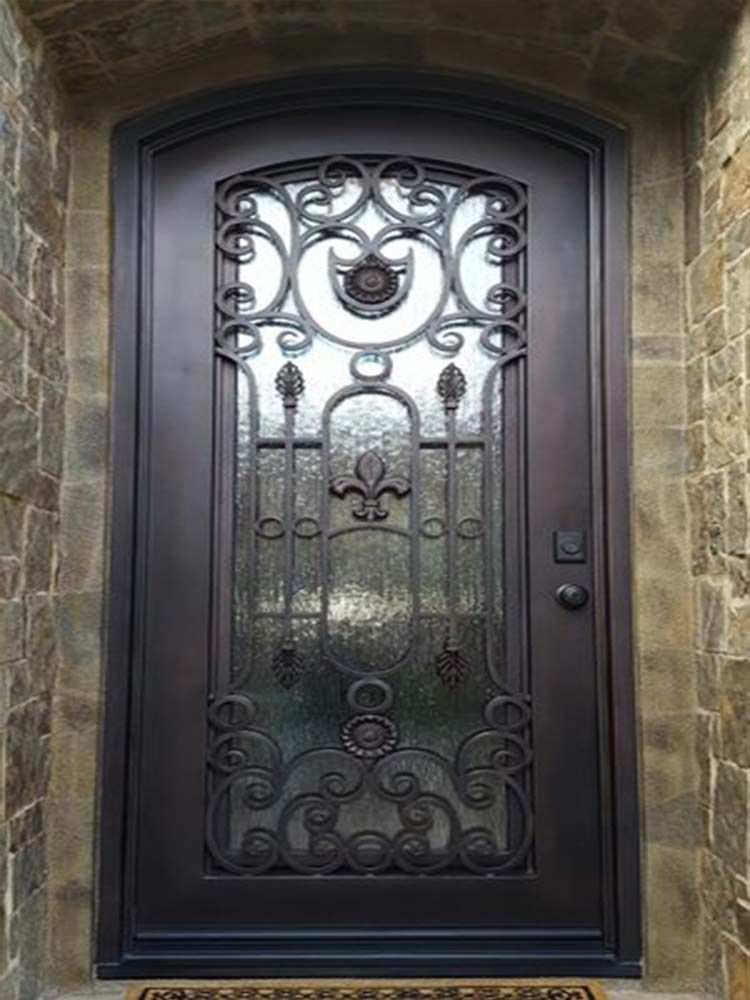 A wrought iron door with two potted plants in front of it.