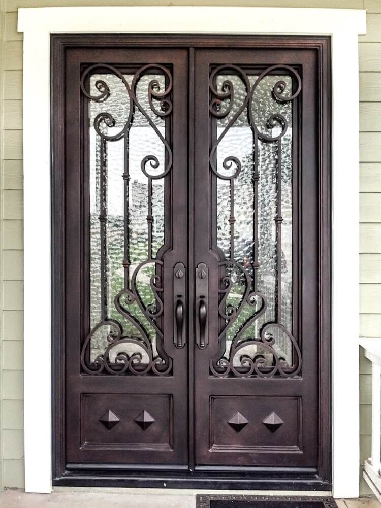A pair of wrought iron doors with stained glass on a house.