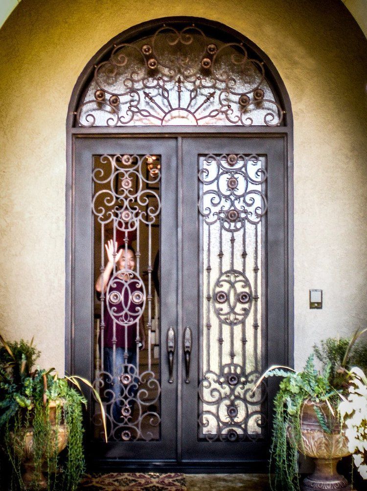 A woman is standing in front of a wrought iron door.
